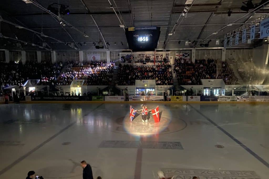 Two figure skaters hold gb and danish flags in opening ceremony at coventry ice rink planet ice before an international ice hockey game team gb vs denmark